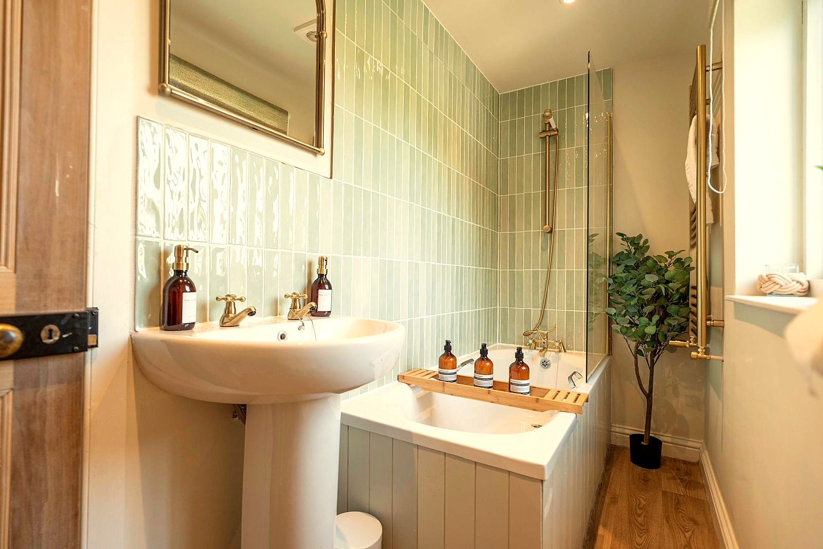 Bathroom with sage-green tiles and brass taps