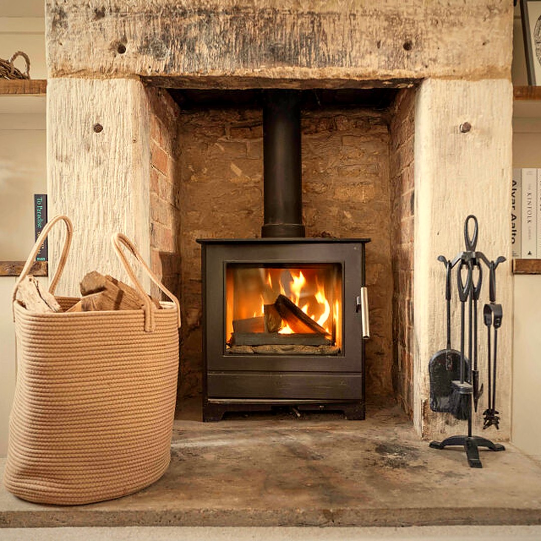 Lit wood burner in an inglenook fireplace