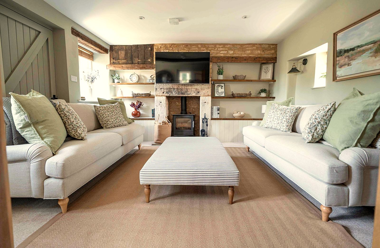 Cotswold holiday let sitting room with sage cushions and oak shelving